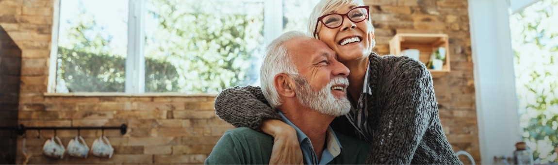 Man and woman with healthy smiles after bone grafting and dental implant tooth replacement