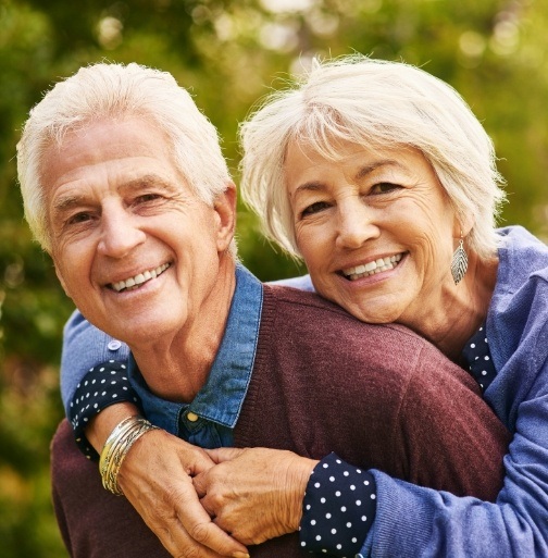 Older couple smiling after dental crown restoration