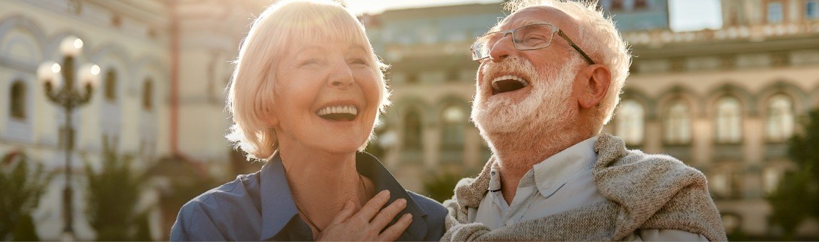 Man and woman laughing together after dental implant supported tooth replacement