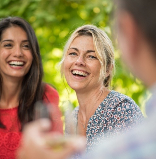 Friends smiling together after dental implant tooth replacement