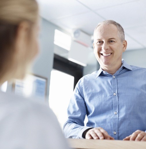 Smiling man checking in at dental office reception desk