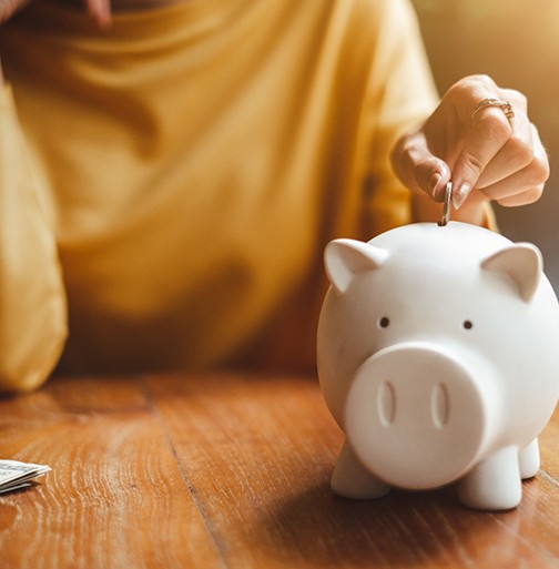 young woman putting money in piggy bank