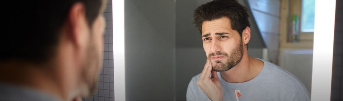 Man in need of emergency dentistry holding jaw in pain