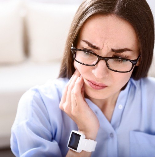 Woman in need of T M J therapy holding jaw in pain