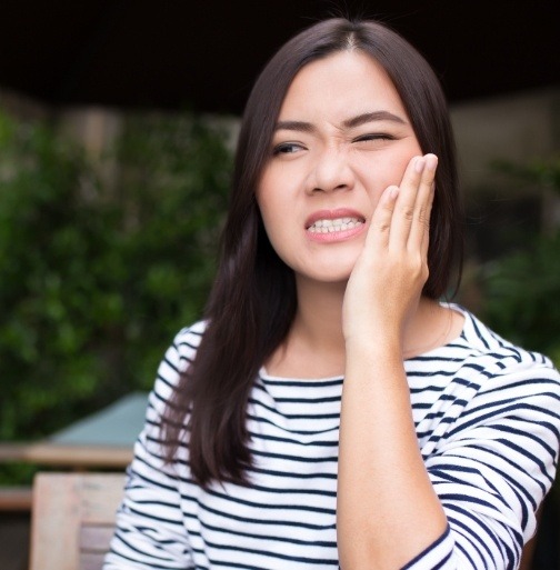 Woman holding jaw in pain before emergency dentistry treatment