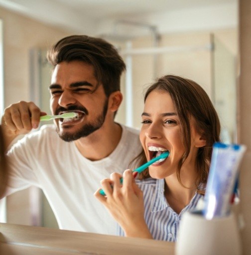 Man and woman brushing teeth to prevent dental emergencies