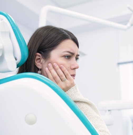 Woman in need of emergency dentistry holding cheek