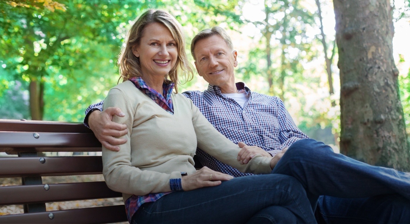 Man and woman smiling together after replacing missing teeth