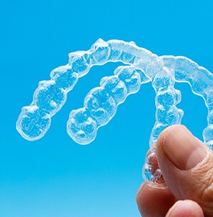 closeup of person holding two clear aligners