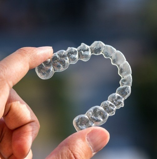 Hand holding an Invisalign tray