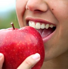 person biting into a red apple   