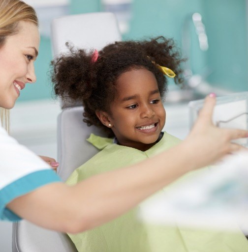 Young girl and dentist looking at smile during children's dentistry visit