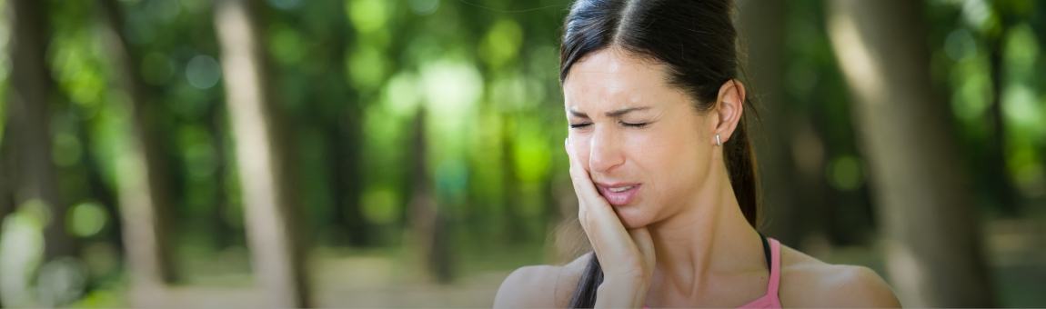 Woman in need of root canal therapy holding jaw in pain