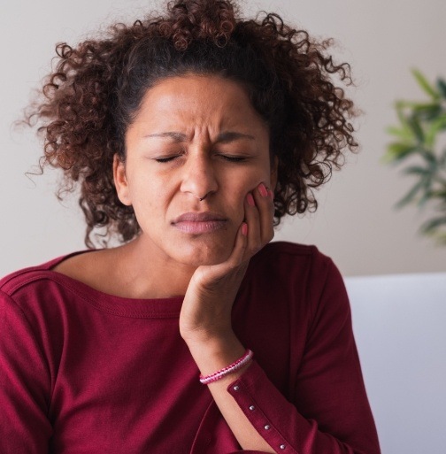 Woman in need of root canal therapy holding jaw in pain