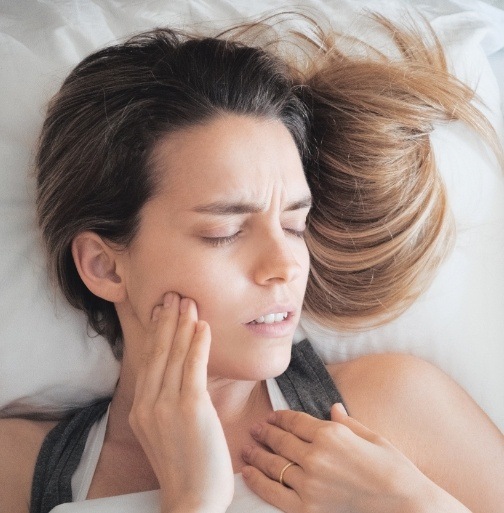 Woman in need of tooth extraction holding jaw in pain