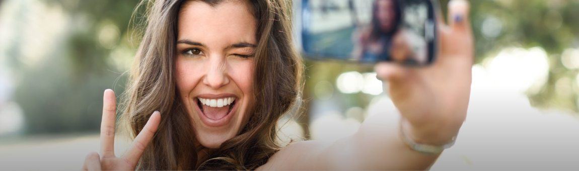 Woman looking at smile after porcelain veneer restoration