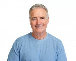 Man in blue shirt smiling with white background