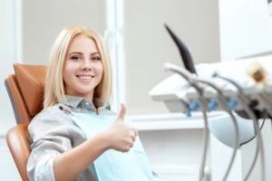 Woman smiling with thumbs up in dental chair