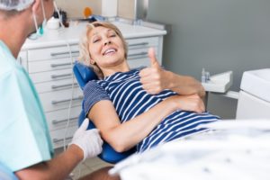 Woman smiling with tumbs up in dental chair