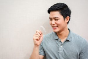 Man smiling while holding Invisalign