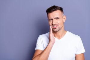 Man with hand on face due to dental pain