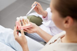 Dentist pointing to model of dental implants with patient