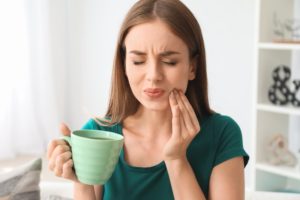 Woman holding a cup with tooth pain