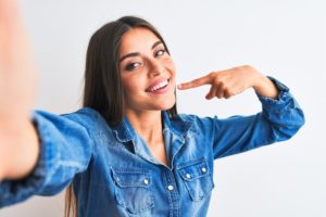 Woman pointing to her beautifully white smile