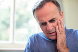 Man with dental pain with hand on his cheek