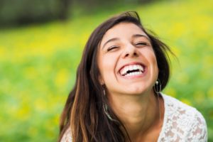 Woman smiling happily outside with green background