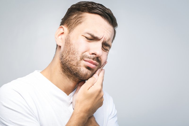 person with tooth pain holding cheek