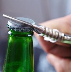 person opening a green glass bottle with a bottle opener   